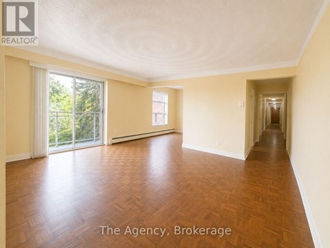 A spacious room with wooden flooring and a long hallway.