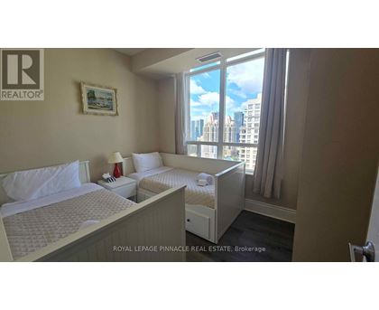 A bedroom with two beds and a window overlooking a cityscape.