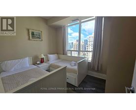 A bedroom with two beds and a window overlooking a cityscape.