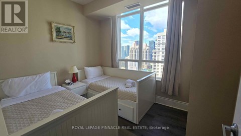 A bedroom with two beds and a window overlooking a cityscape.