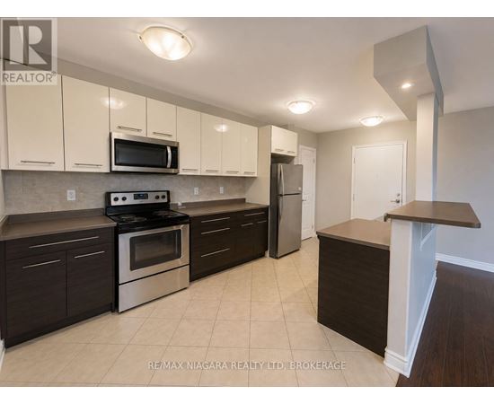 A kitchen with a stove top oven, microwave, refrigerator, and cabinets.
