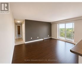 A spacious room with wooden flooring and a large window overlooking the outdoors.