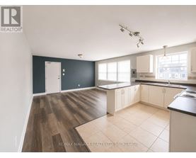 A spacious kitchen with dark grey walls and wooden flooring.