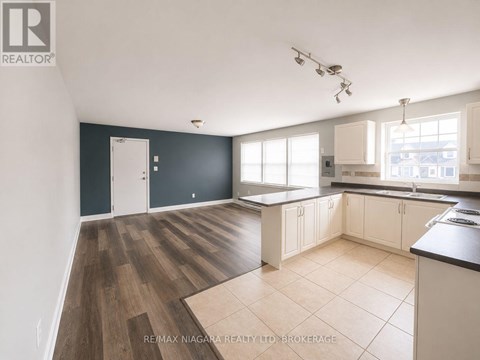 A spacious kitchen with dark grey walls and wooden flooring.
