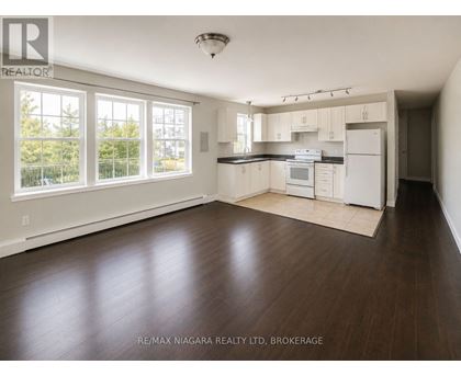A well lit kitchen with white appliances and wooden floors.