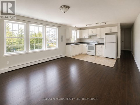 A well lit kitchen with white appliances and wooden floors.