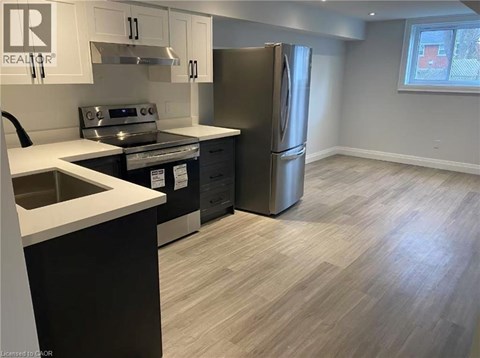 A kitchen with a stainless steel refrigerator, sink, and cabinets.