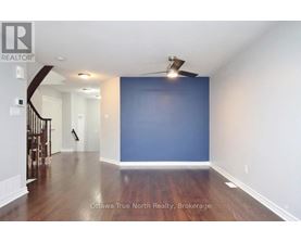 A spacious room with a staircase on the left and a ceiling fan above.