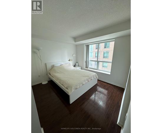 A bedroom with a bed, nightstand, and lamp.