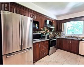 A kitchen with a stainless steel refrigerator and wooden cabinets.