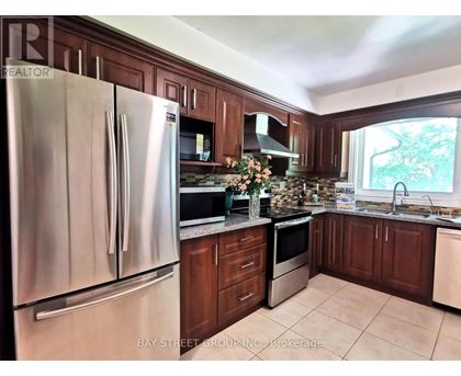 A kitchen with a stainless steel refrigerator and wooden cabinets.
