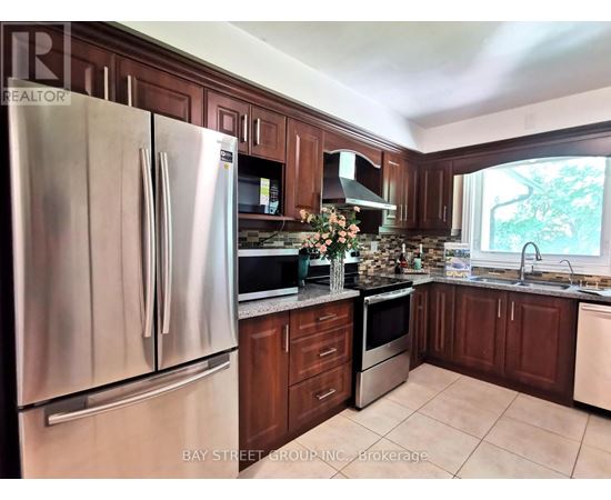 A kitchen with a stainless steel refrigerator and wooden cabinets.