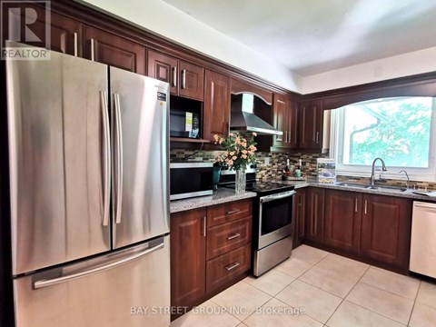 A kitchen with a stainless steel refrigerator and wooden cabinets.