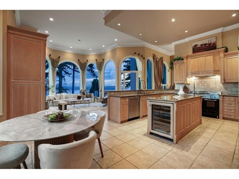 A kitchen with a table and chairs in front of a window with a view of the ocean.