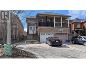 A black car is parked in front of a brick house with a garage.
