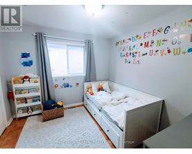 A white bedroom with a white bed and a white wall with alphabet magnets.