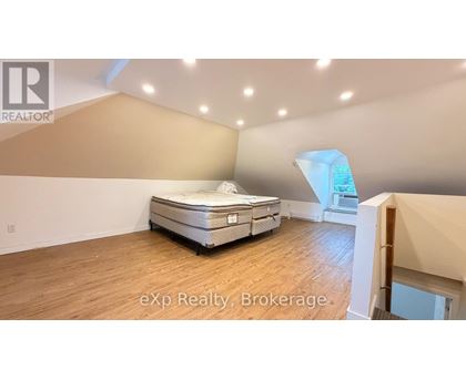 A bed in a room with a brokerage logo.
