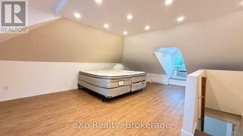 A bed in a room with a brokerage logo.
