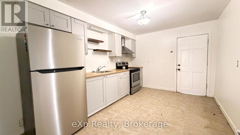 A kitchen with a stainless steel refrigerator and white cabinets.