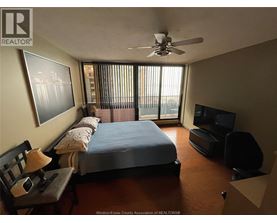 A bedroom with a bed, chair, and television.