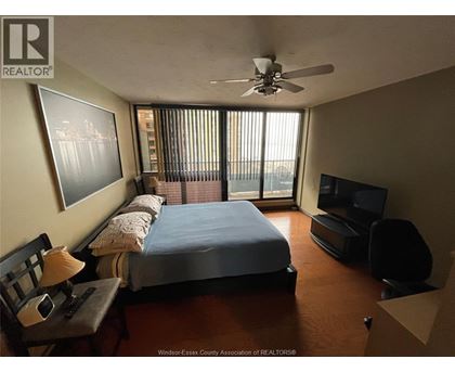 A bedroom with a bed, chair, and television.