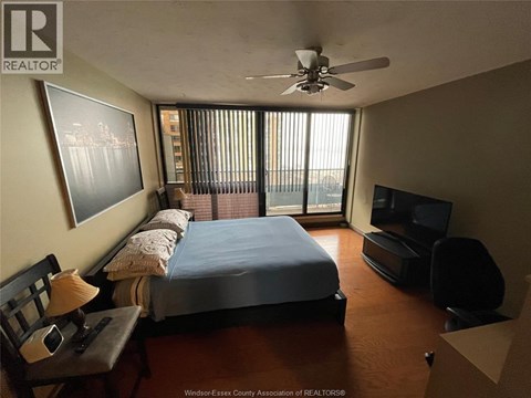 A bedroom with a bed, chair, and television.