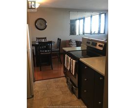 A kitchen with a black stove top oven and black chairs.