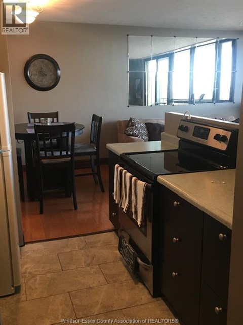 A kitchen with a black stove top oven and black chairs.