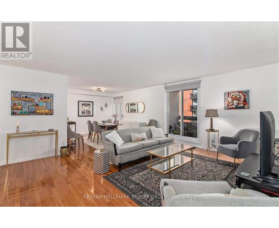 A living room with a grey couch and a painting on the wall.