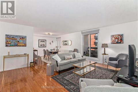 A living room with a grey couch and a painting on the wall.