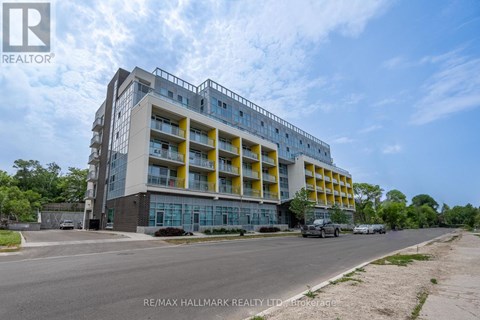 A multi-story building with a mix of yellow and grey balconies is shown.