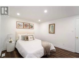 A bedroom with a white bed and a white lamp on a side table.