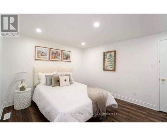 A bedroom with a white bed and a white lamp on a side table.