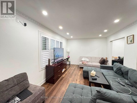 A living room with a grey couch and a television on a wooden cabinet.