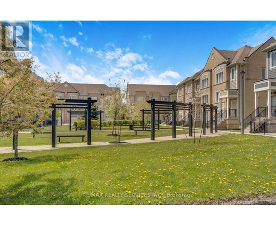 A sunny day at a park with a gazebo and apartment buildings in the background.