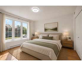 A bedroom with a large bed, a window with curtains, and a painting on the wall.
