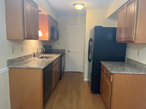 A kitchen with wooden cabinets and a black refrigerator.