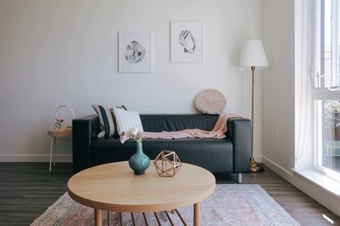 A living room with a black couch, a wooden table, and a vase on it.