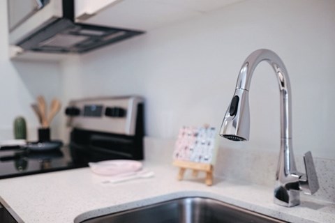 A kitchen sink with a modern faucet and a small wooden calendar on the counter.