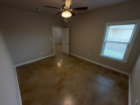 A room with a ceiling fan and a window with blinds.