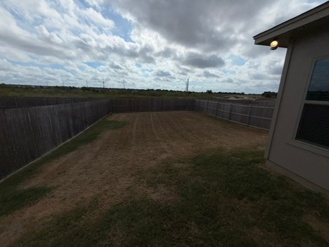 A backyard with a wooden fence and a grassy area.
