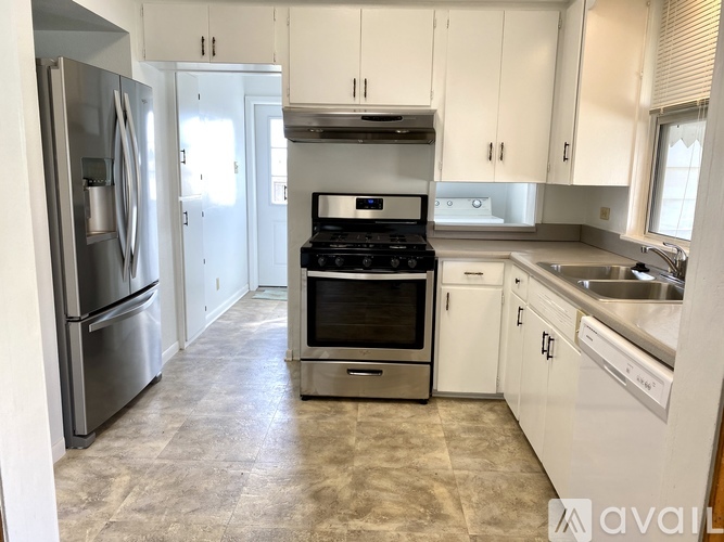 A kitchen with white cabinets and a stainless steel refrigerator.
