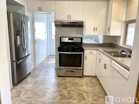 A kitchen with white cabinets and a stainless steel refrigerator.