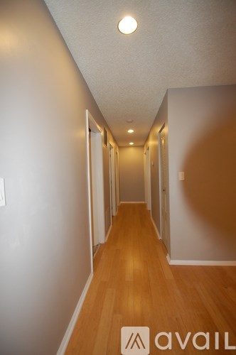 A hallway with wooden floors and white walls.