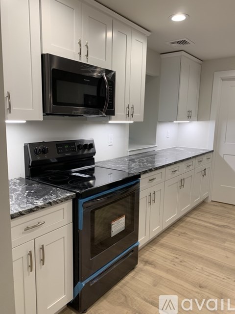 A kitchen with white cabinets and a black stove top oven.