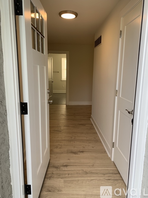A hallway with white doors and wooden floors.