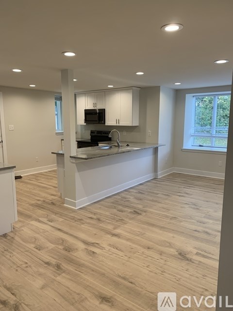 A kitchen with wooden flooring and white walls.