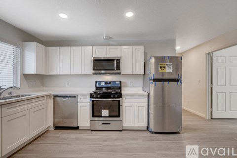 A kitchen with white cabinets and stainless steel appliances is available for rent.