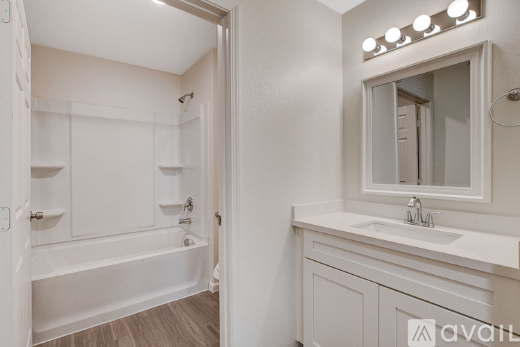 A white bathroom with a tub, sink, and mirror.