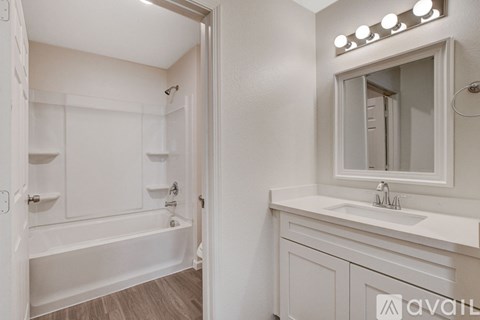 A white bathroom with a tub, sink, and mirror.
